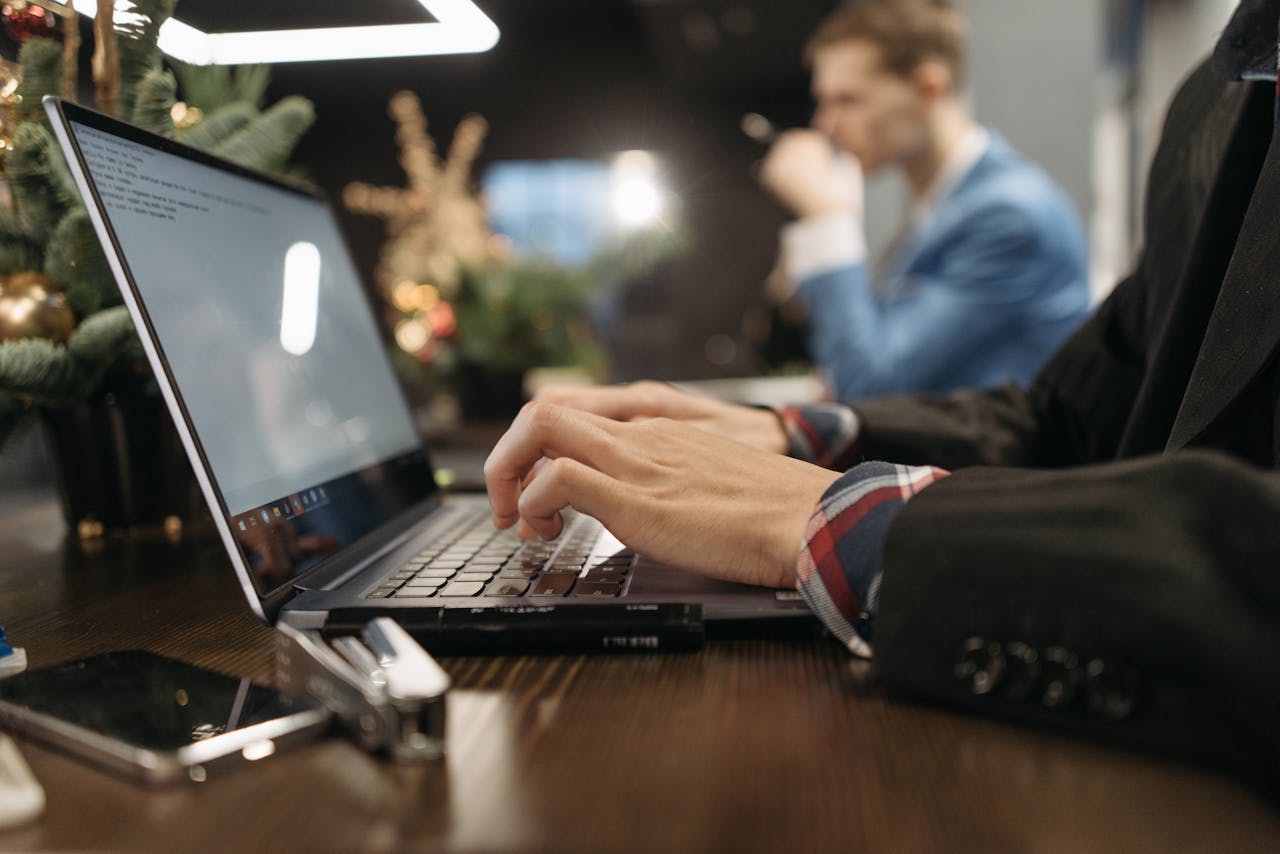The Art of Drawing Readers In: Your attractive post title goes here A professional man typing on a laptop in an elegant indoor office setting with a blurred background.