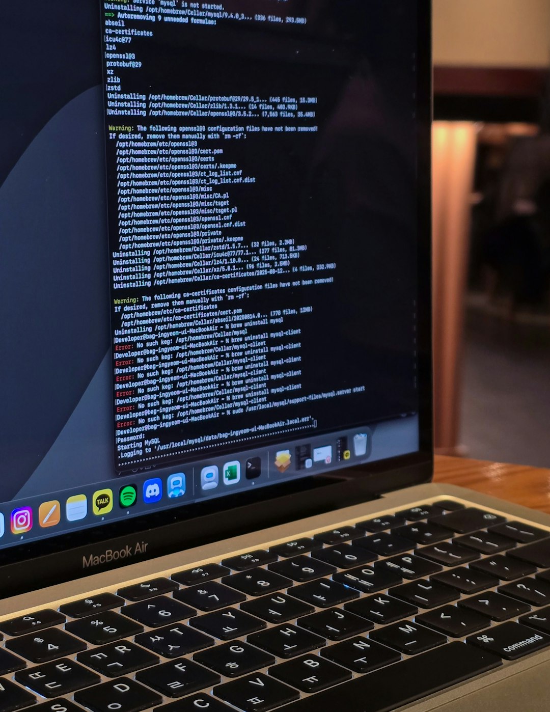 services-01 Close-up of a MacBook Air displaying terminal commands and code logs in a cozy indoor workspace with warm ambient lighting, capturing a developer’s workflow.